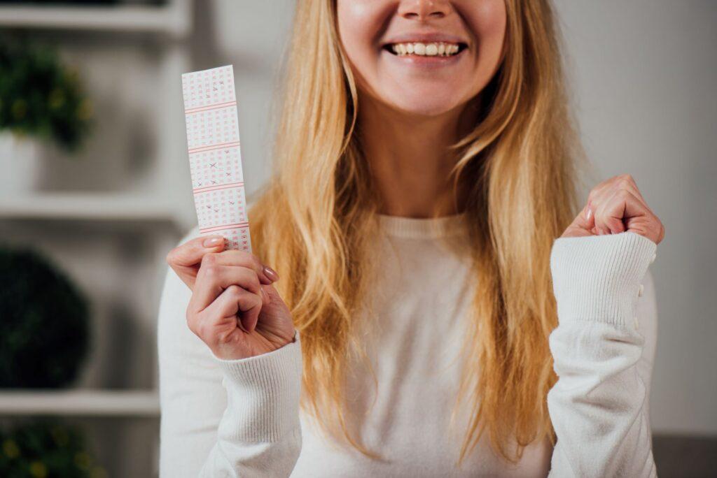 Glückliche Frau hält Lottoschein