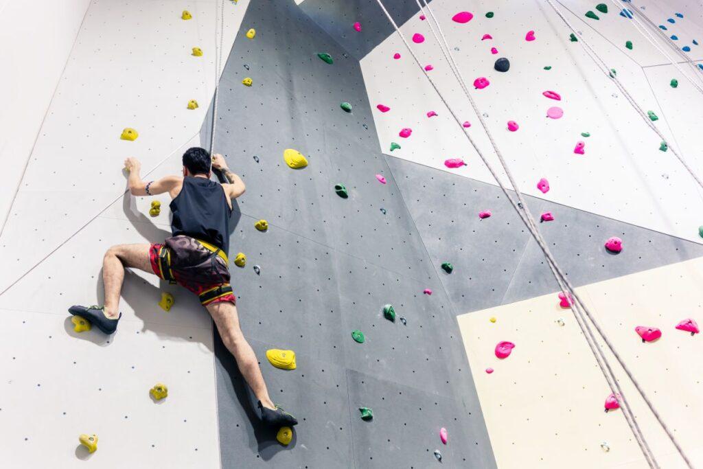 Sportlicher Mann erklimmt Kletterwand – Teil eines Action-Wochenendes mit Paintball Berlin