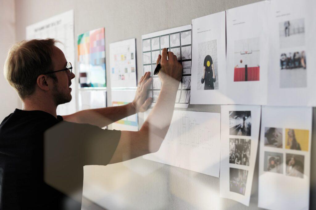 Mann entwickelt eine Marketingstrategie mit ausgedruckten Materialien an der Wand – inklusive Konzepten zu Werbemitteln und Etiketten drucken lassen