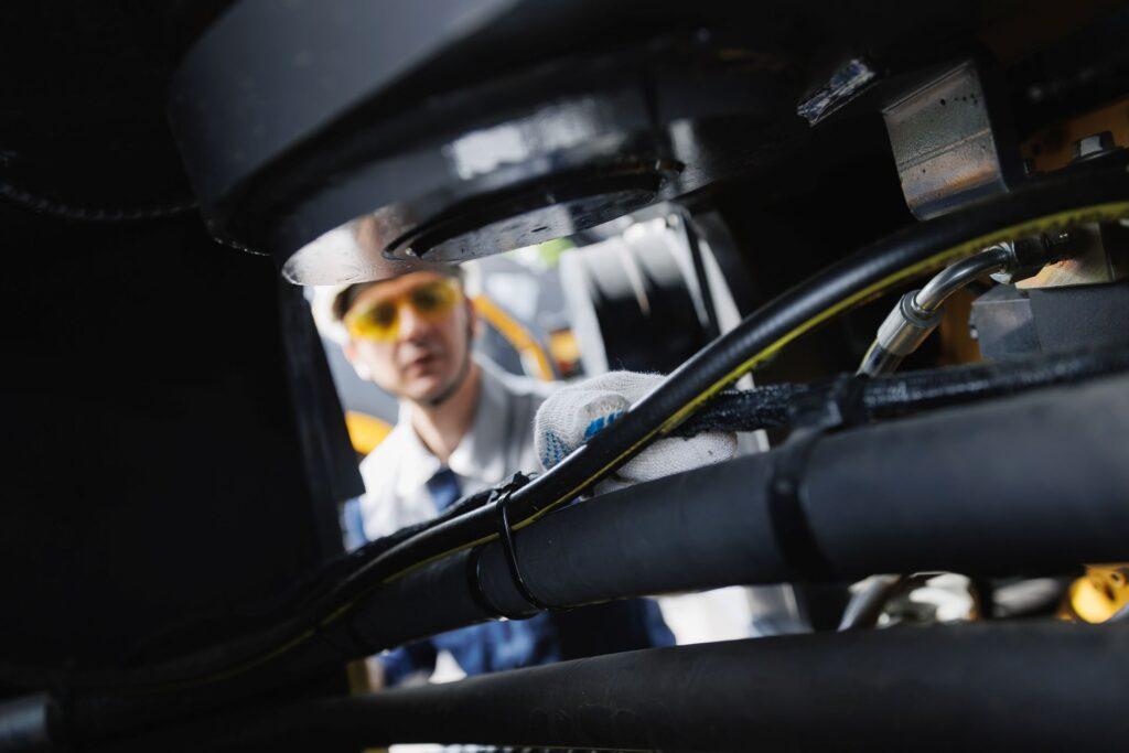 Techniker überprüft industrielle Schläuche und Verbindungen in einer Anlage